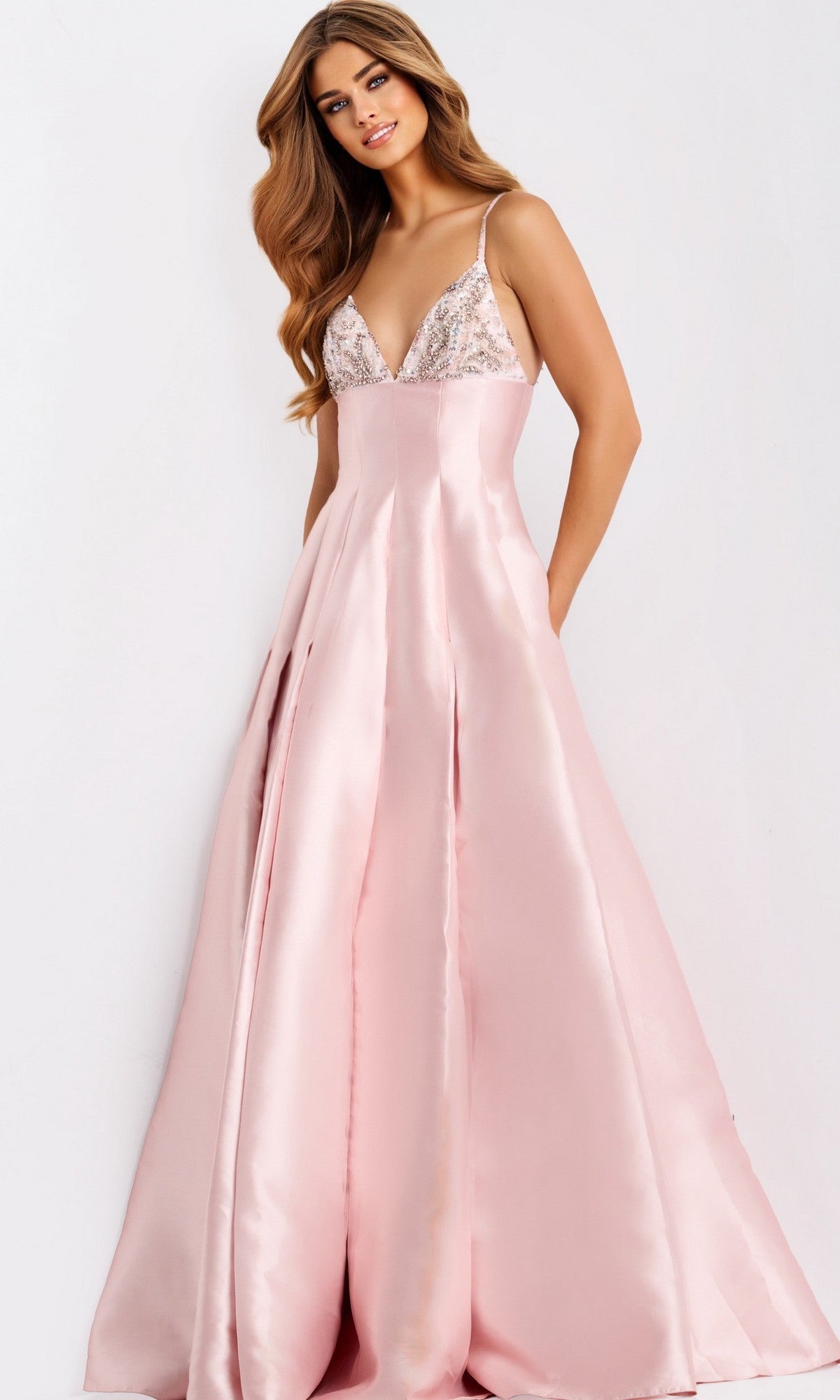 A woman models the Jovani 48732, a sleeveless floor-length pale pink satin A-line prom dress with a deep V-neck and beaded embellished bodice, standing against a plain white background.